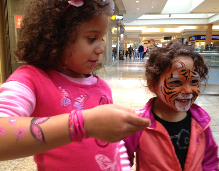 girls showing off their face painting of butterfly and tiger